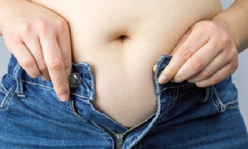 Mujer con sobrepeso abrochándose el pantalón. Diabetes de tipo 2.