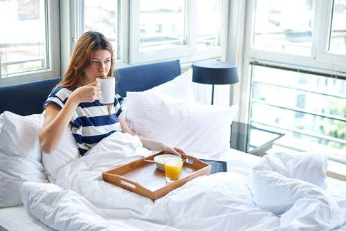 Kvinde nyder morgenmad i sengen