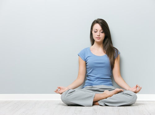 Kvinde sidder i skrædderstilling og gør sig klar til at dyrke yoga som et par