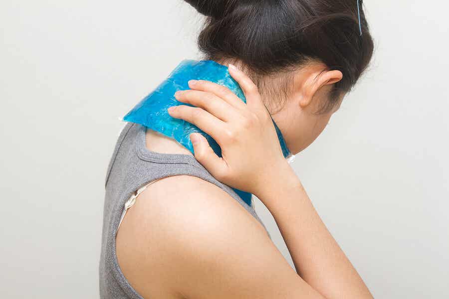Femme plaçant une compresse froide sur son cou pour soulager la douleur.