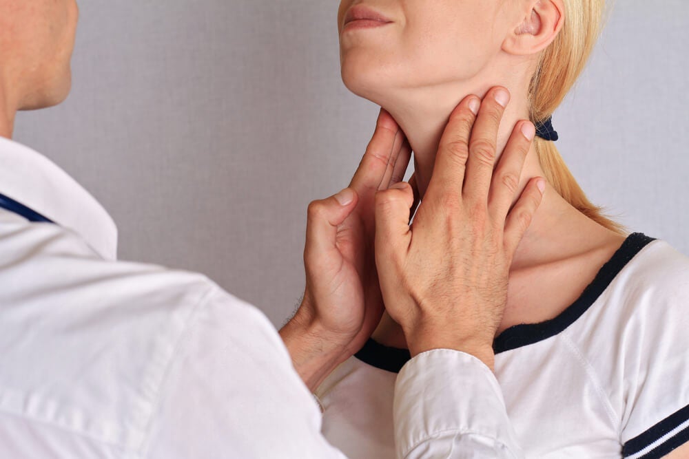 Cuello de mujer siendo palpado por un mÃ©dico para el control de la tiroides.