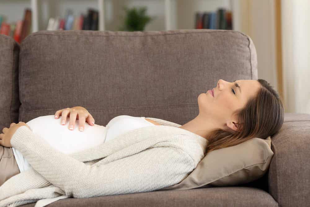 Femme enceinte allongée sur le canapé avec inconfort. Colique typique de la grossesse.