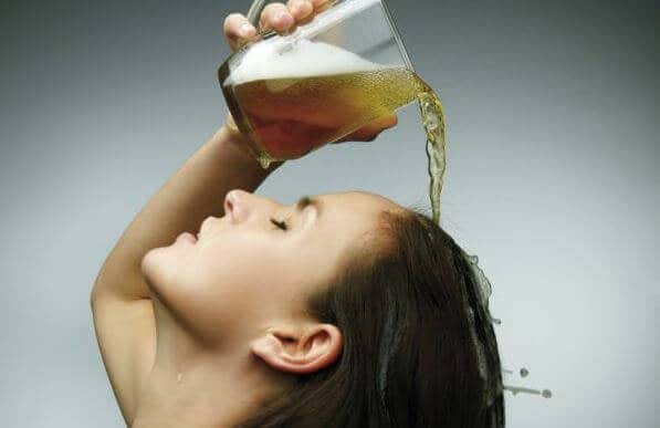 Garota lavando o cabelo com cerveja para tratar a caspa