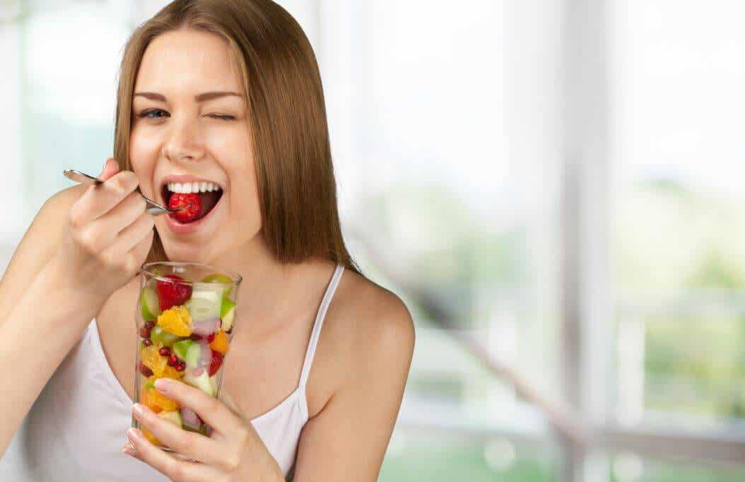 Femme qui mange une salade de fruits.