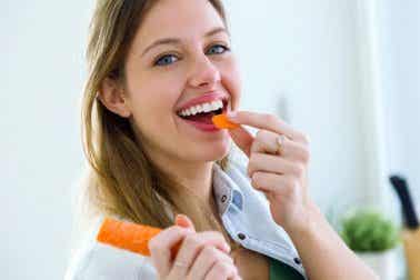 A woman eating a carrot.
