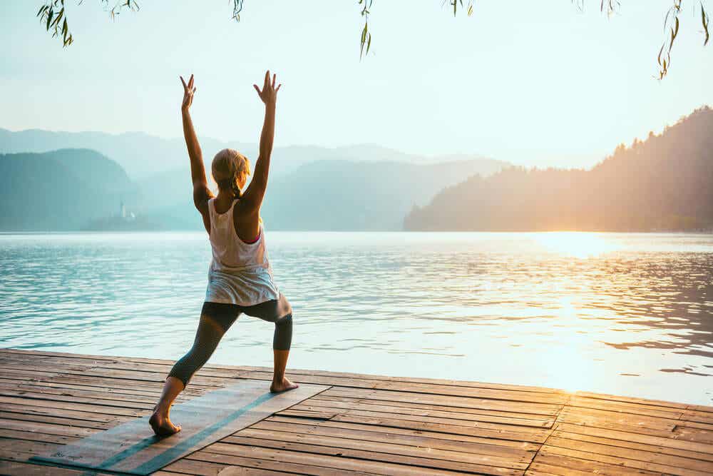 Femme qui fait du yoga face à un lac.