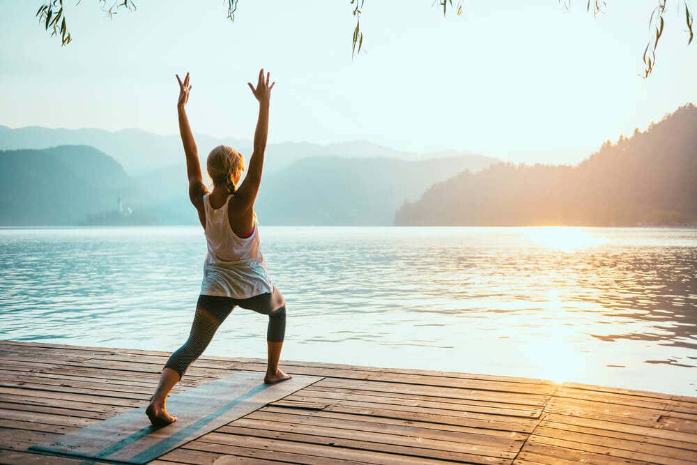 Femme qui fait du yoga face à un lac.