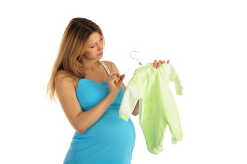 Gravid kvinde ser på pris på babytøj og tænker på at spare penge før en fødsel
