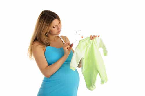Gravid kvinde ser på pris på babytøj og tænker på at spare penge før en fødsel