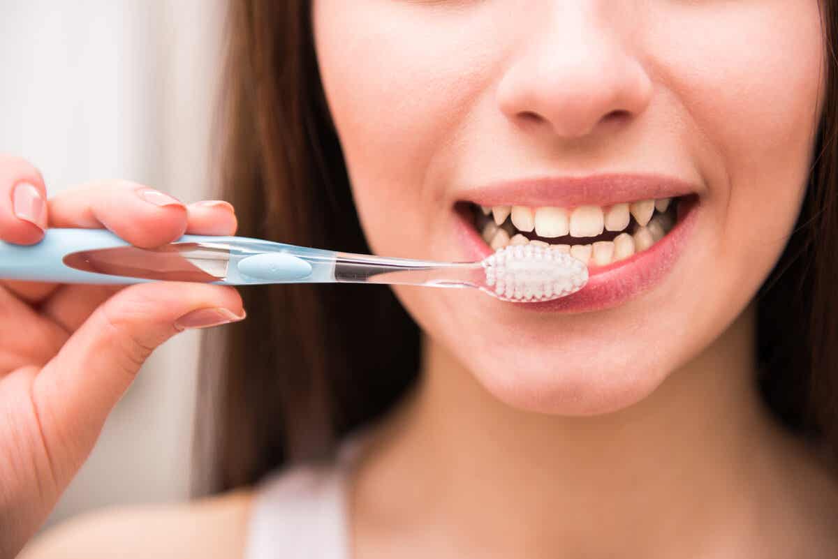 La femme se brosse les dents à cause de la xérostomie.